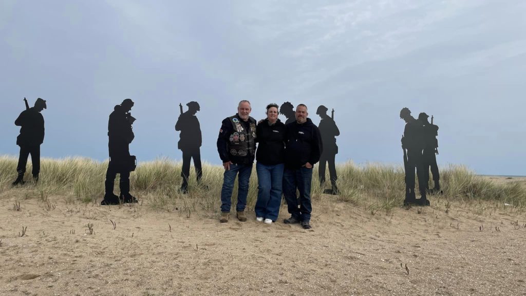 H.O.G. members standing on the beach.