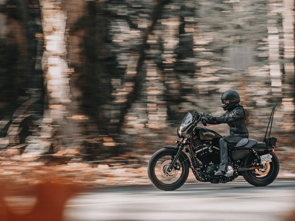 ANDRA NEDELCU riding her motorcycle along a wooded road.